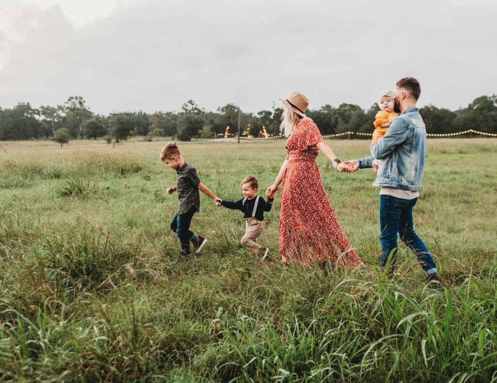 Family walking hand in hand through a grassy field