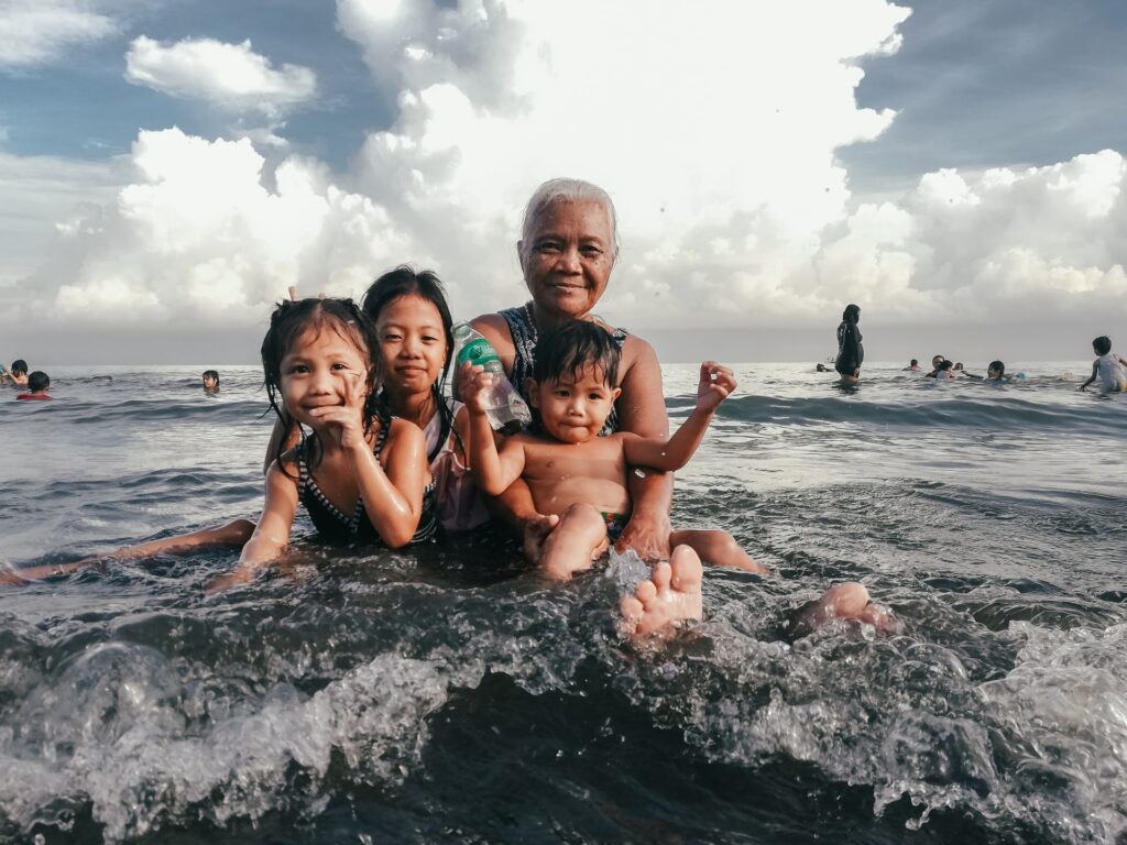 Grandmother and three young children enjoying a day at the beach, capturing a heartwarming family moment