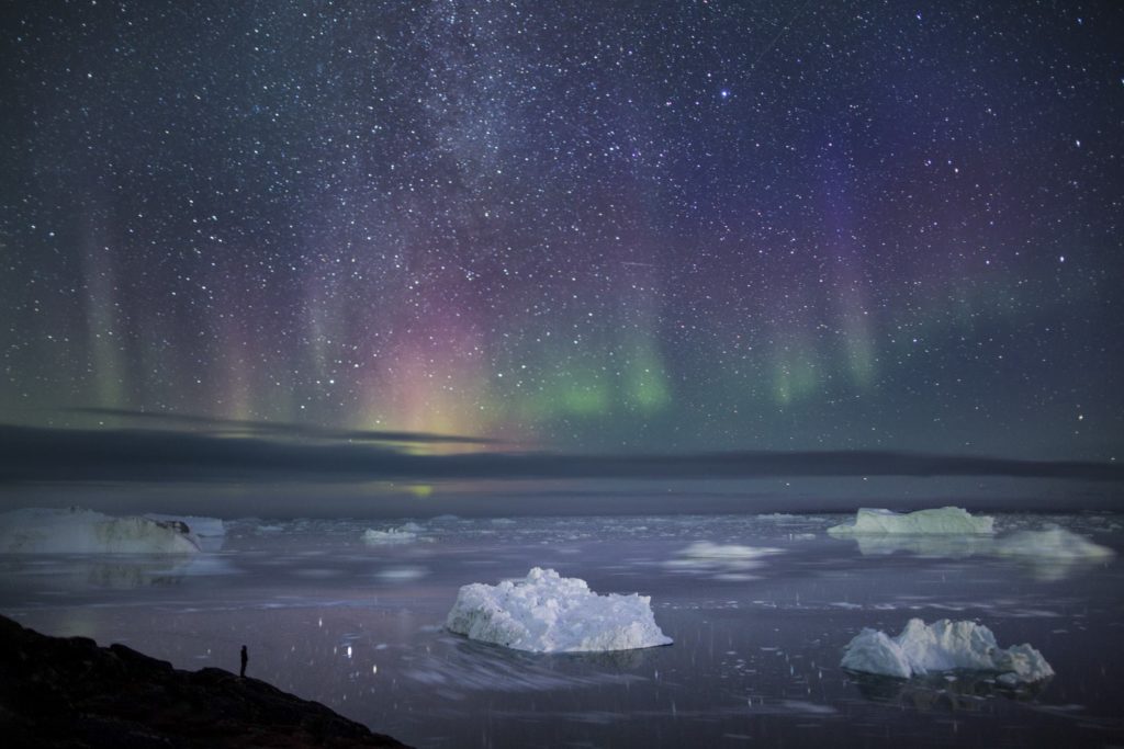 The northern lights over water and icebergs.