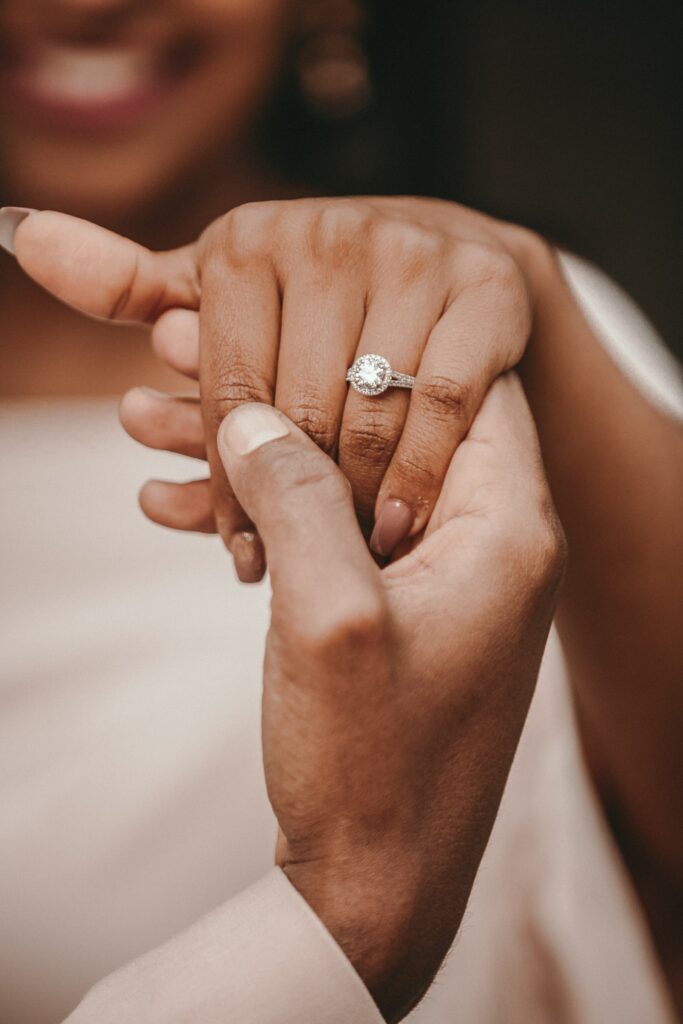 Close-up of a couple's hands, with the focus on the engagement ring on the woman's finger