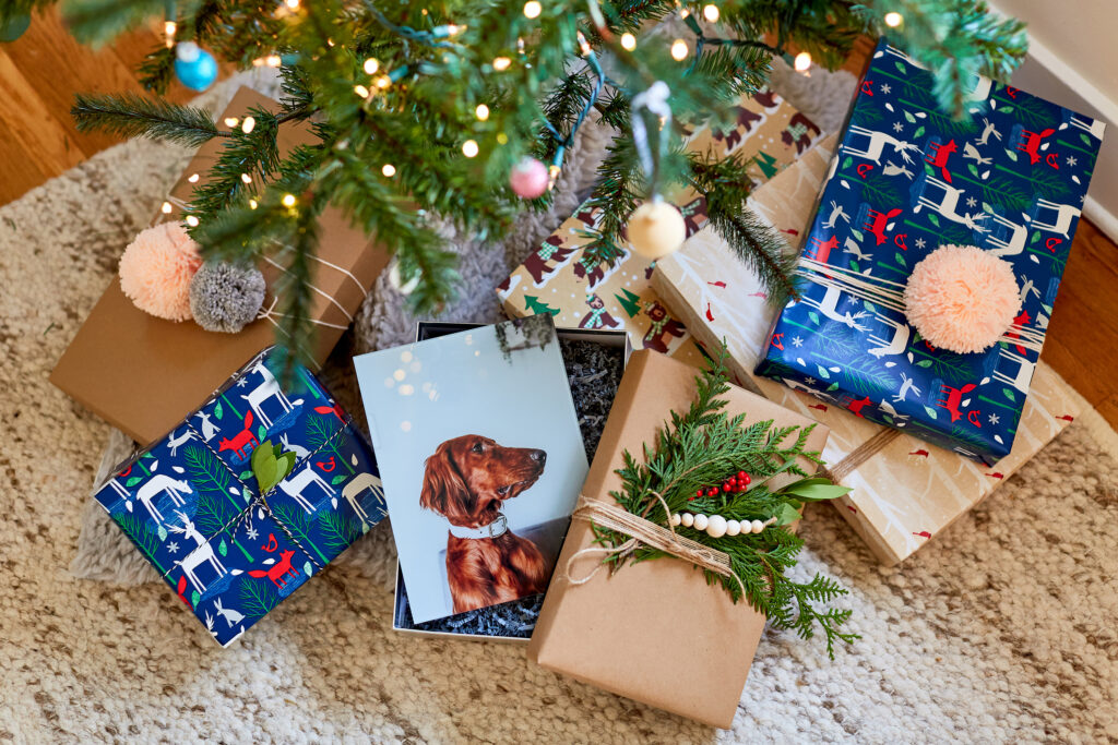 Dog photo gift in a black frame, placed on a wooden table with holiday decorations around