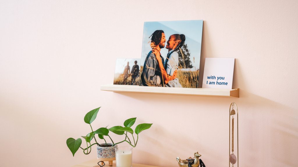 The perfect 3rd anniversary gift, a set of glass prints, sits on a wood shelf above a cutely styled entryway table.