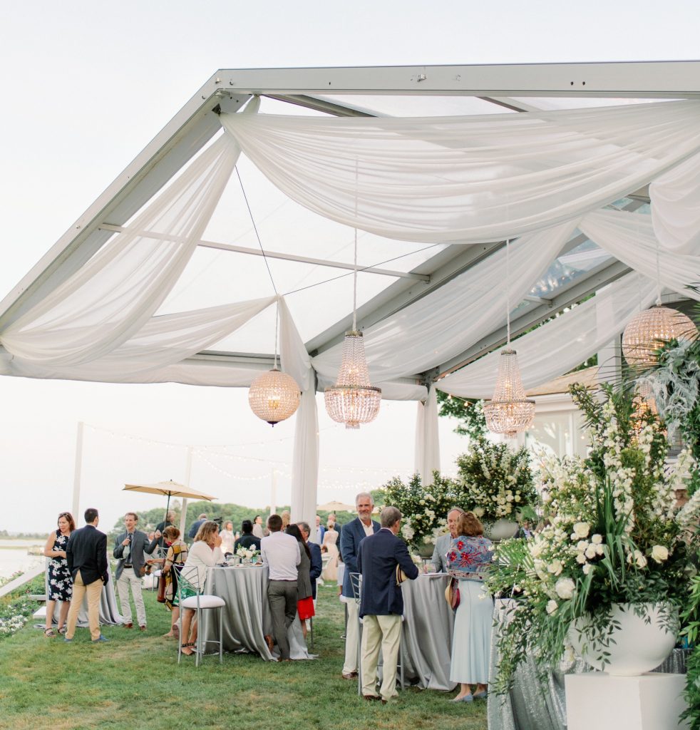 Wedding guests mingling under an elegant tent creating a beautiful outdoor reception atmosphere