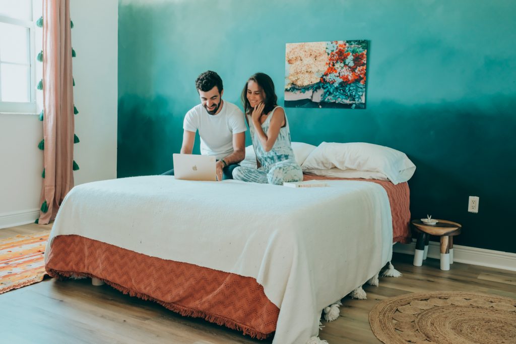 Woman and man on bed smile at laptop