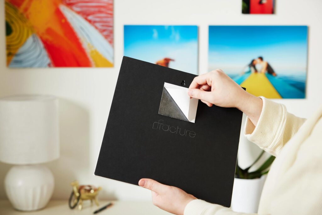 Peeling the liner off of a piece of Wall Tape adhered to the back of a Fracture glass print. This is the fastest way to put up glass prints with zero wall damage.