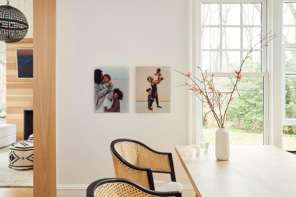Two glass prints are mounted next to large windows in a gorgeous, well-lit, minimalist kitchen. The photos feature a mom with her two kids.