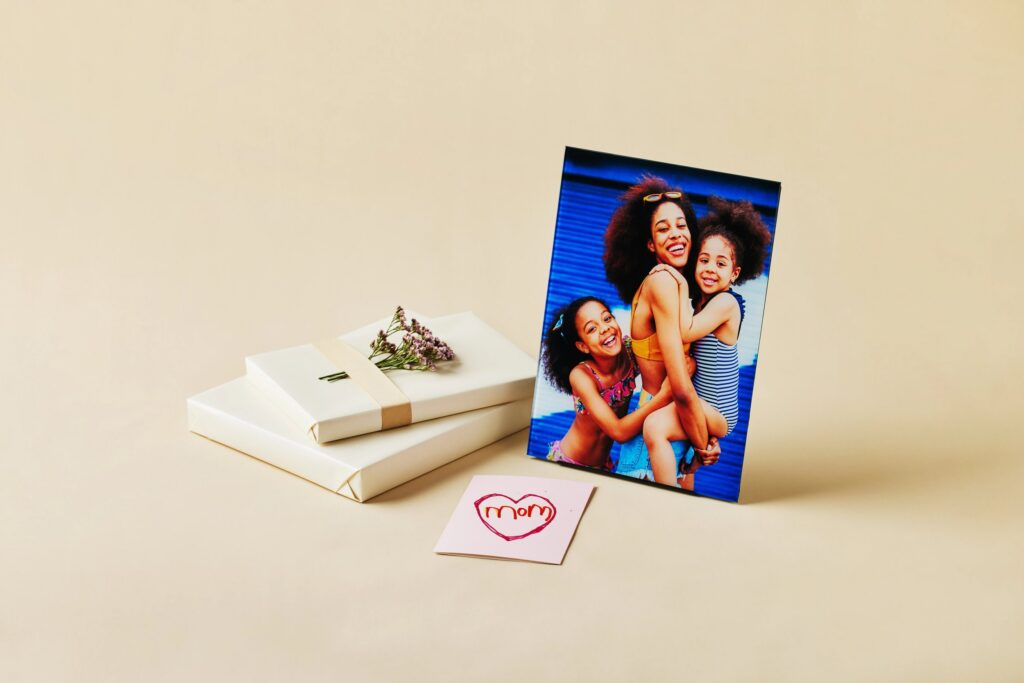 Mother's Day photo of mom with two daughters printed on glass, sitting next to a gift box and a handwritten card.