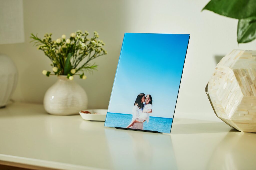 Mother's Day photo of mom holding her young daughter on a beach, printed on glass and sitting in a low-profile stand on a table.