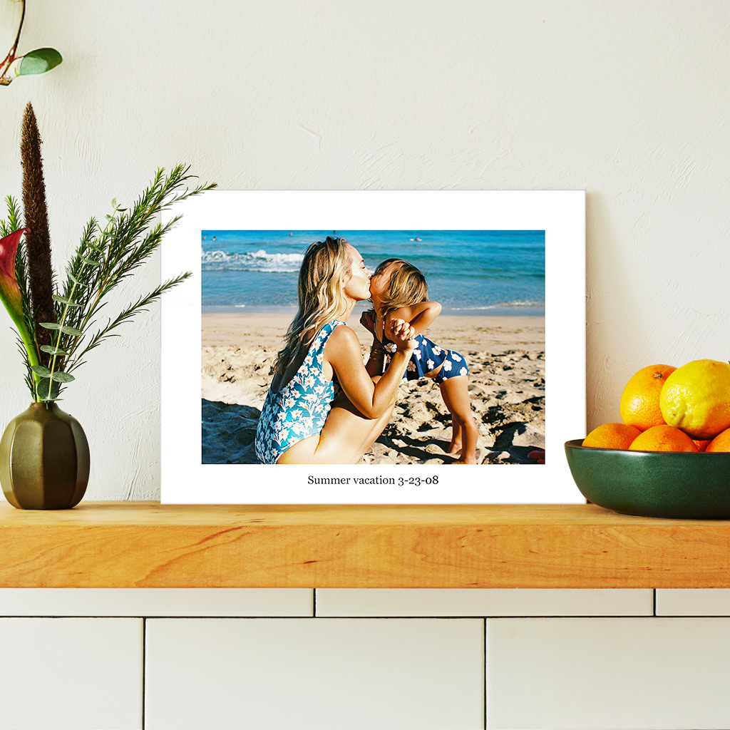 A beautifully printed photo no glass of a mother and daughter at the beach. A white border with custom text that shows the date of their summer vacation makes the photo pop beautifully