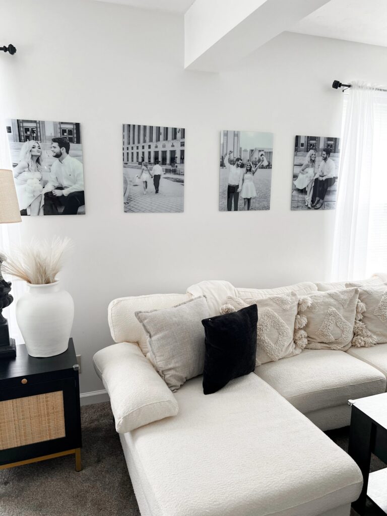 Black & white gallery wall of wedding glass prints, arranged beautifully in a row above a cream couch and neutral living room space