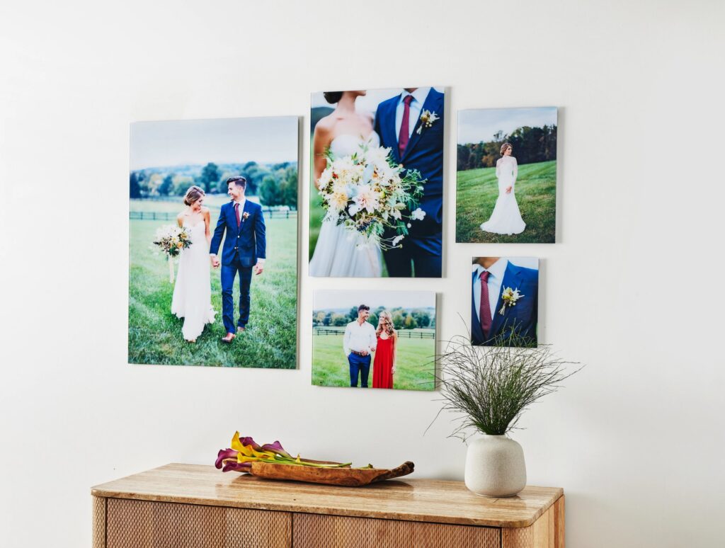 A gallery wall of glass prints featuring a variety of wedding photos: a couple's portrait, a close-up of the bouquet, a shot from the engagement, a portrait of the bride, and a close-up of the groom's boutonniere.